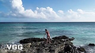 A naked petite girl is playing on the sandy beach