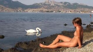 A hot girl is walking naked on the riverbank and enjoying herself