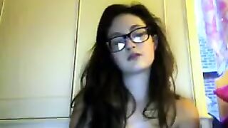 A cute girl in glasses undresses during a video chat