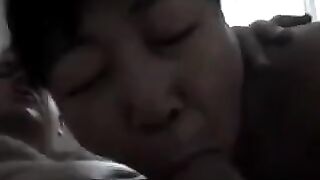 An Asian woman practices her blowjob skills on her man in a steamy homemade scene