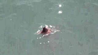 A pair of naked people enjoy themselves in the middle of the sea