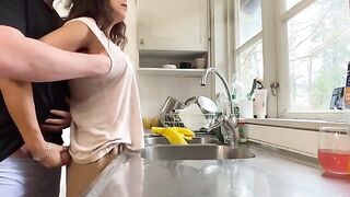 A sexy brunette with big tits is being fucked from behind in the kitchen