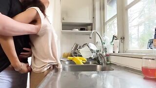 A sexy brunette with big tits is being fucked from behind in the kitchen